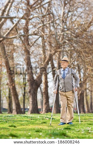 Elderly gentleman walking with crutches in park