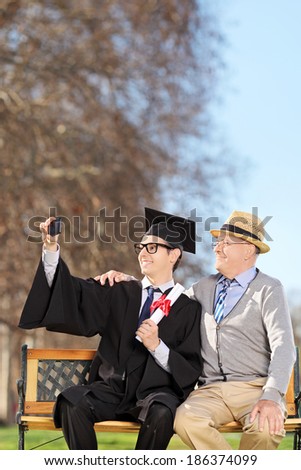 Student and his proud father taking selfie outdoors