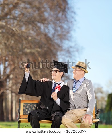 Male student and his proud father taking selfie in park shot with tilt and shift lens