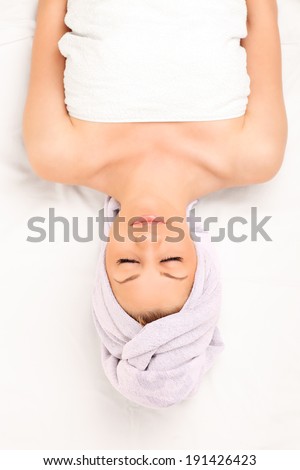 Woman lying on a massage table isolated on white background, shot upside down