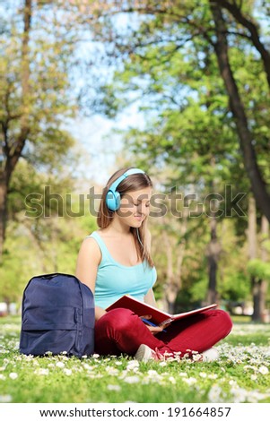 Young woman studying in park seated on a meadow