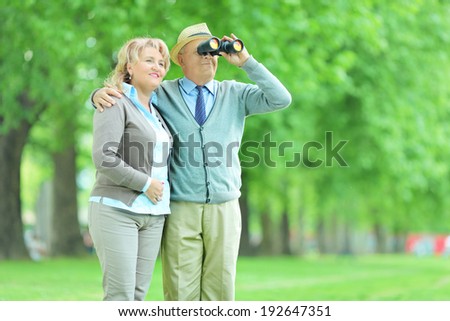 Senior couple looking through binoculars outdoors