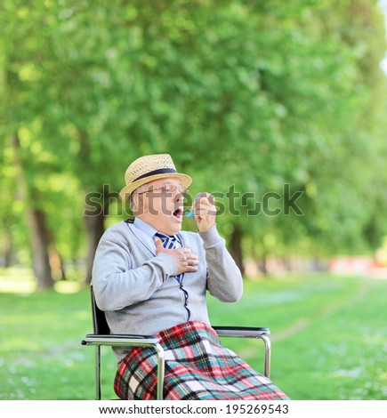 Senior man having an asthma attack in park shot with tilt and shift lens