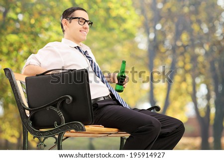 Businessman taking a break in park with a beer bottle