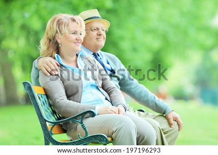 Relaxed mature couple sitting on a wooden bench in park