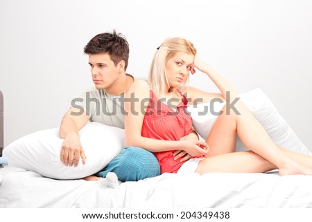 Bored young couple sitting in a bedroom
