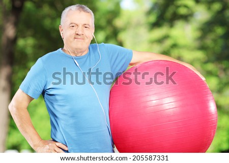 Mature sporty man holding a fitness ball in a park