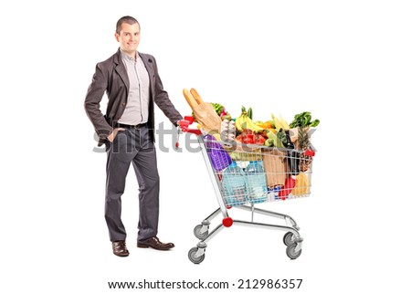 Handsome man with shopping cart full of groceries isolated on white background