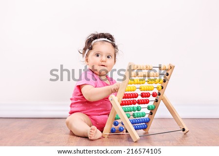 Little girl playing with an abacus seated on wooden floor