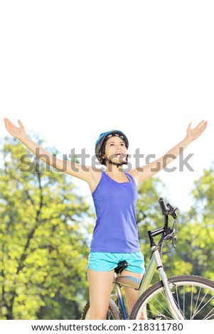 Happy female biker posing with raised hands on a mountain bike outdoors