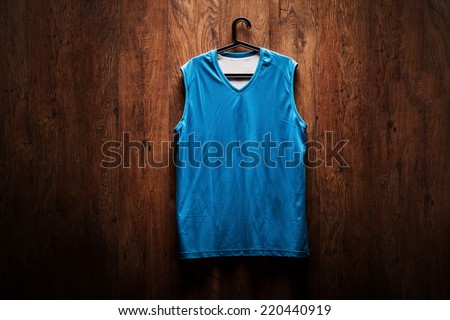 Blue basketball jersey hanging on a wooden wall on a hanger