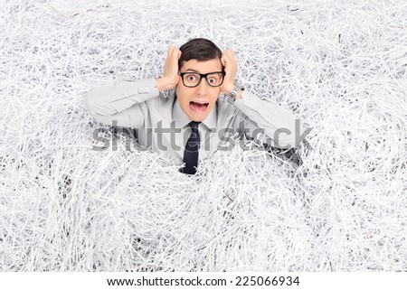 Terrified man panicking in a pile of shredded paper