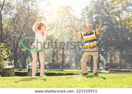 Mature couple exercising with hula hoops in park on a sunny day