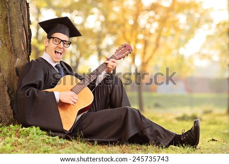 Graduate student playing acoustic guitar in park