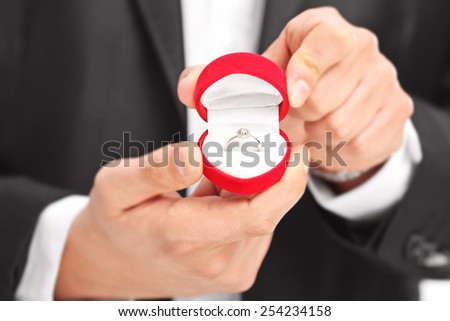 Close-up on a man holding an engagement ring with the focus on the ring