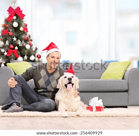 Man and a dog with Santa hats sitting by a sofa at home shot with tilt and shift lens