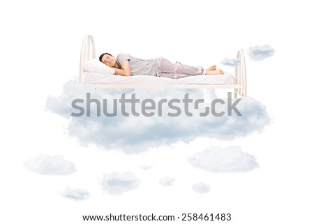 Young man sleeping on a comfortable bed in clouds isolated on white background