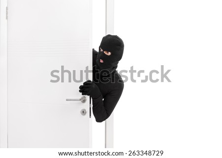 Studio shot of a stealthy thief breaking into a room through a door and carefully looking around isolated on white background