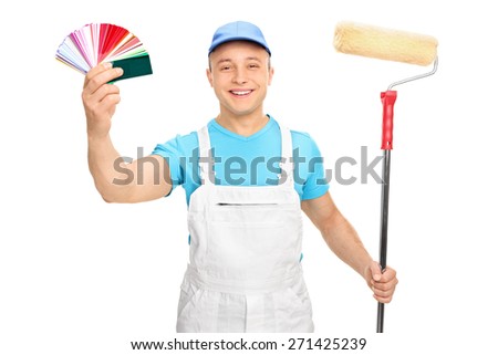 Young male painter in a white jumpsuit holding a paint roller and color guide isolated on white background