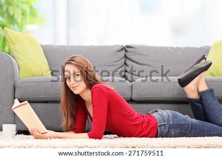 Young woman reading a book and lying on the floor at home
