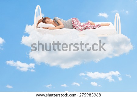 Relaxed young woman sleeping on a comfortable bed in the clouds