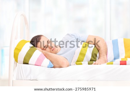 Relaxed man sleeping in a comfortable bed covered with a blanket at home