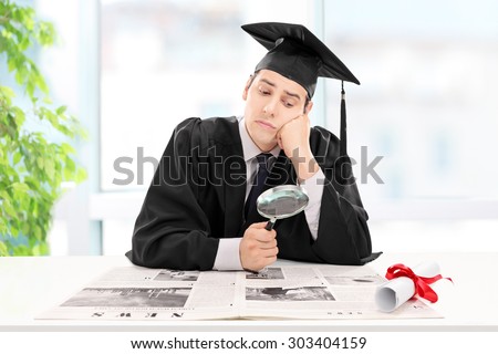 Student looking for a job in a newspaper at home with a magnifying glass