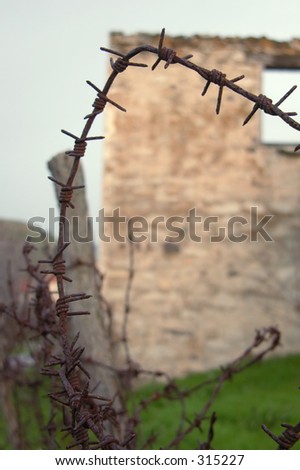 A ruined and abandoned house with a barbed wire fence