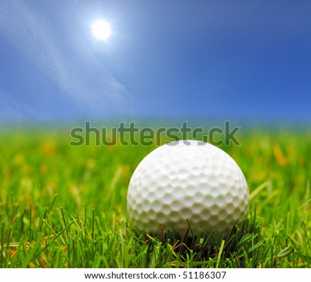 A golf ball on a green grass and a blue sky