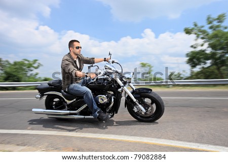 A young man riding a motorcycle on an open road