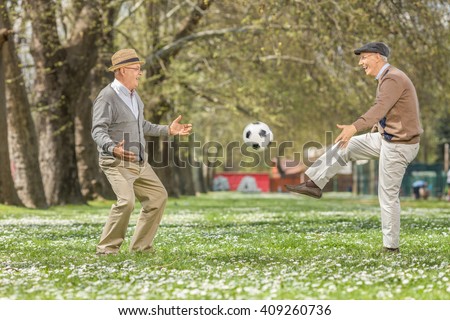 Two joyful seniors playing football in a park on a beautiful spring day