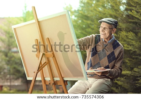 Elderly man painting on a canvas outside