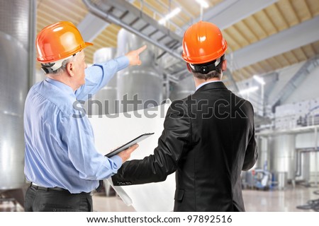 A team of construction workers with orange helmets at work place in a factory