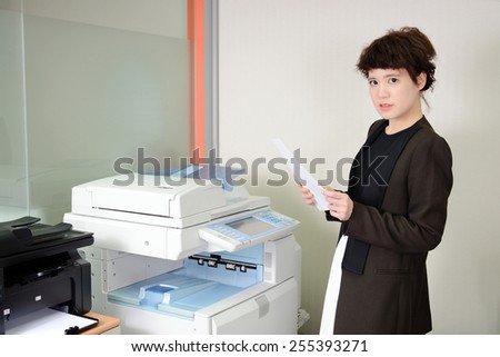 Young Asian business woman using a copy machine.