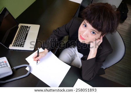 Young, beautiful businesswoman with laptop and notebook in office. Top view.