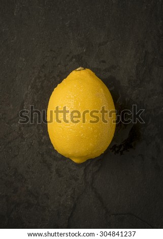 A single lemon on a dark slate background