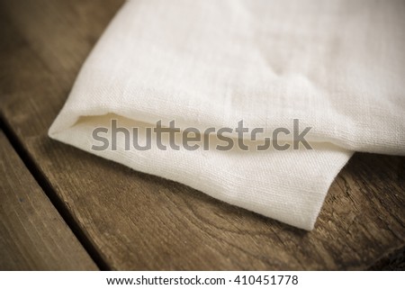 Folded white cotton fabric or linen on wooden surface.