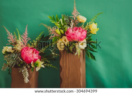 two bouquets in wooden vase on a green background