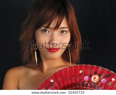 Very seductive young asian woman with a fan on a black background