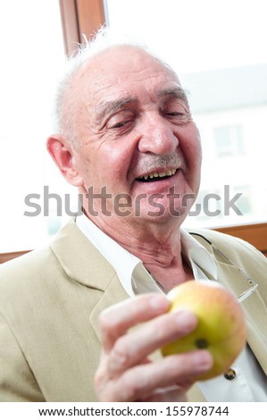 Closeup profile on a smiling old man with apple