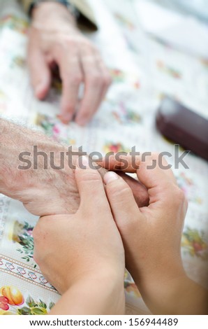 Young woman hand touches and holds an old man\'s wrinkled hands