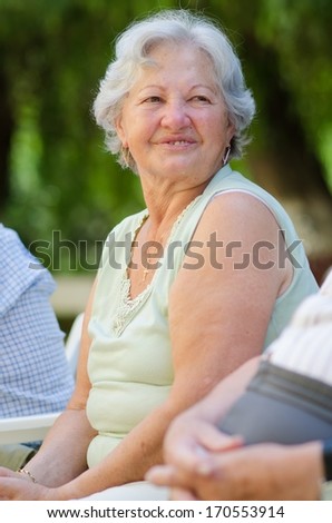 Happy old woman sitting and relaxing in the nature