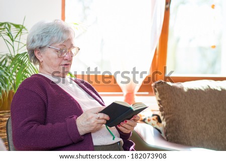 elderly woman with hands holding Bible