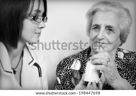 Doctor giving medicines and explaining how to take pills to elderly woman at home