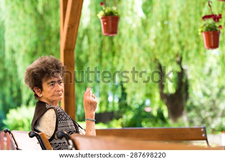 Old woman siting on bench and smoking