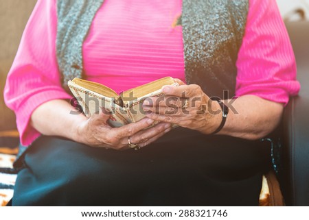 Senior woman with hands holding Bible