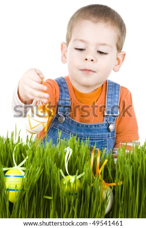 Easter egg hunt, boy searching for easter eggs hidden in fresh green grass