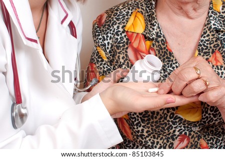 Doctor woman giving pills to an elderly woman and teaching her how to take them isolated on white background