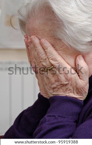 A crying elderly woman covering her face