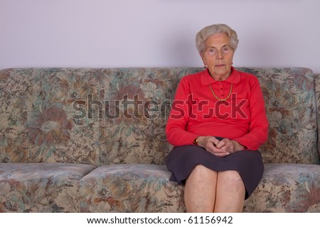 An old woman sits on the couch